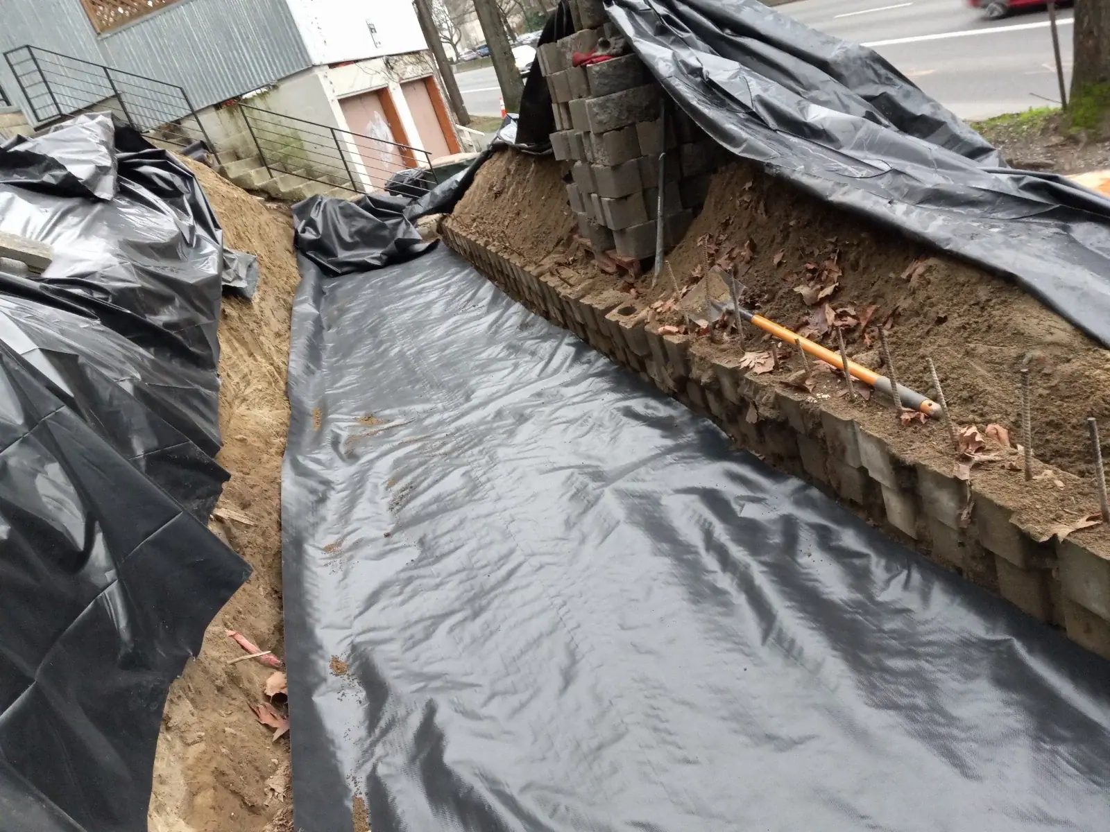 Footing trench along the block retaining wall lined with black waterproofing membrane
