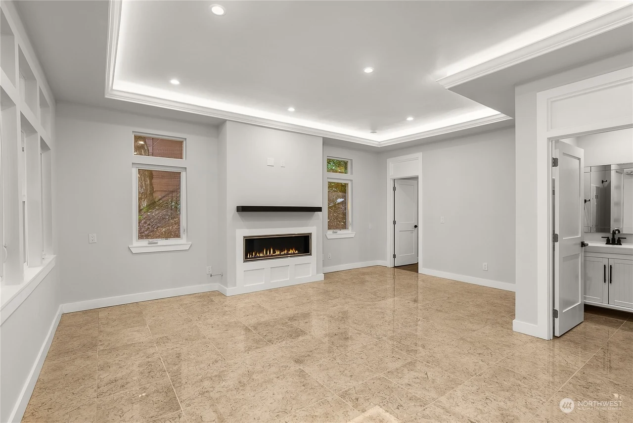 Living room with a linear fireplace flanked by windows