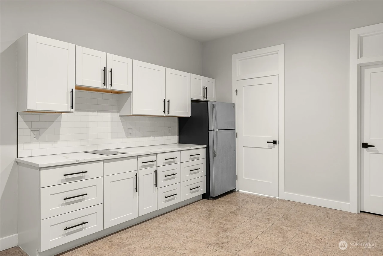 Secondary galley kitchen with white shaker cabinets and a stainless refrigerator