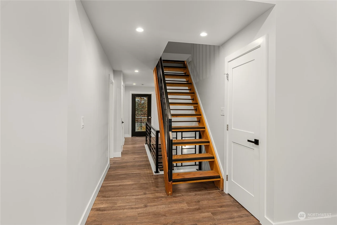 Hallway with an open wood-tread stair and white doors