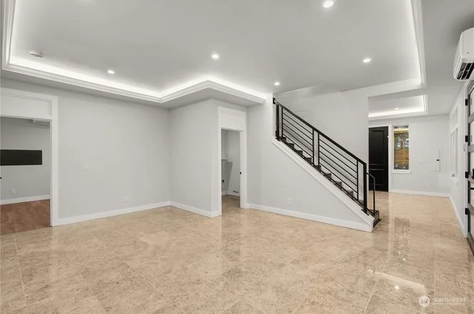 Lower-level room with an LED cove ceiling and the black-railed stair