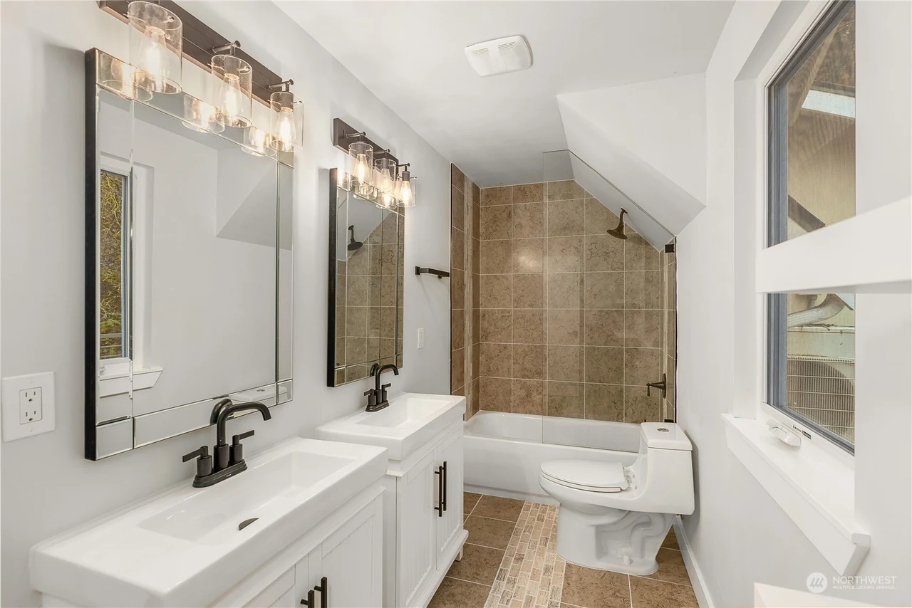 Bathroom with a double vanity and a tiled tub-and-shower surround