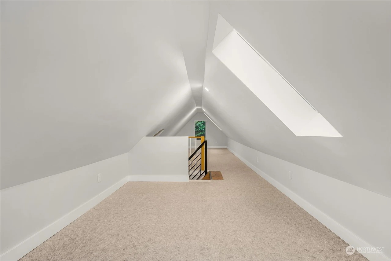 Attic bonus room with a vaulted ceiling, skylight, and carpet