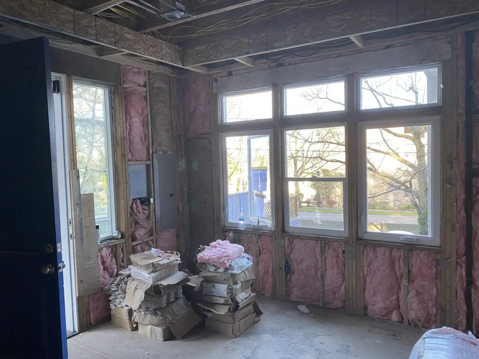 Insulated room with a large window and materials staged on the subfloor