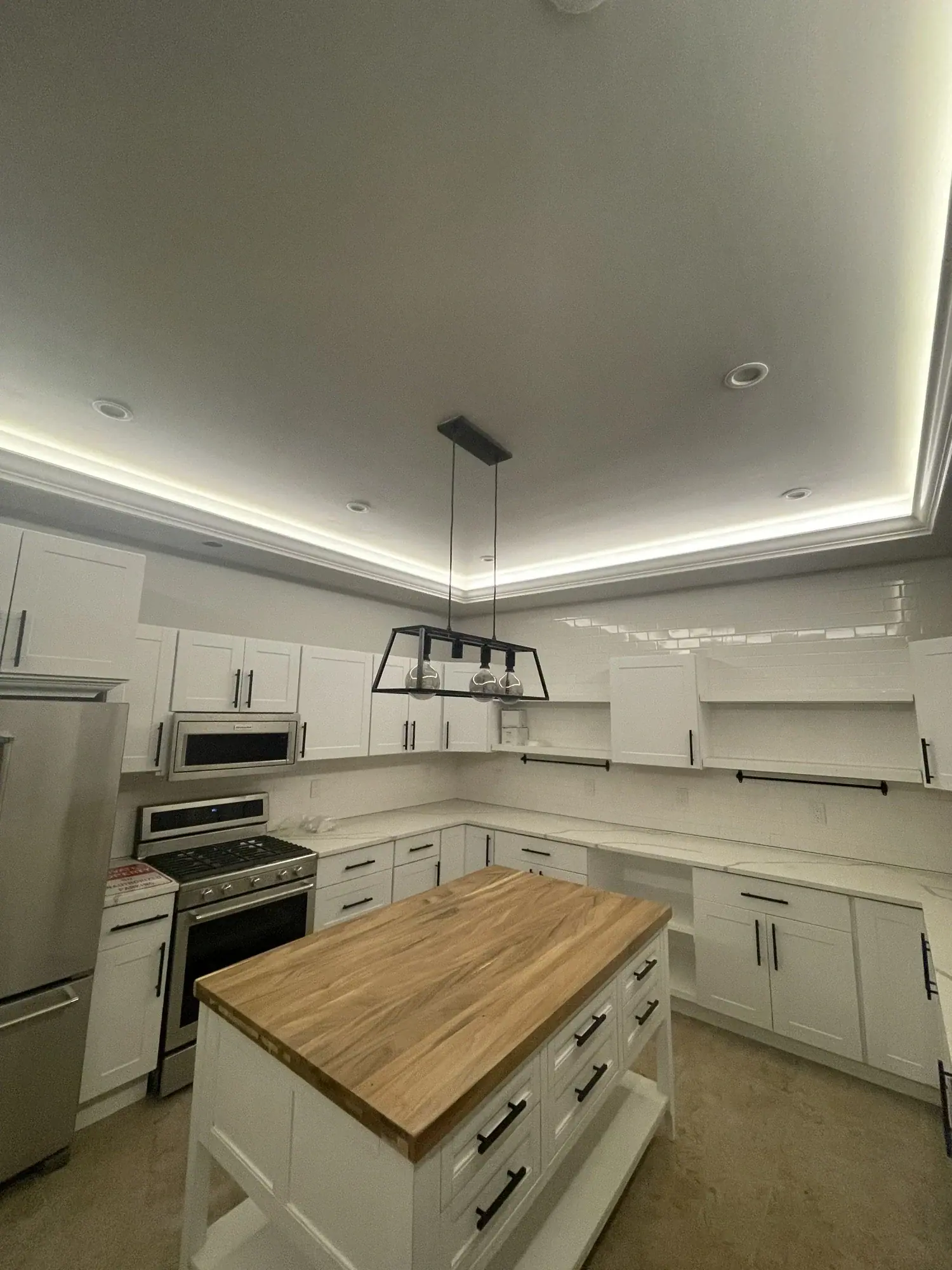 Kitchen with white shaker cabinets, a butcher-block island, and stainless appliances