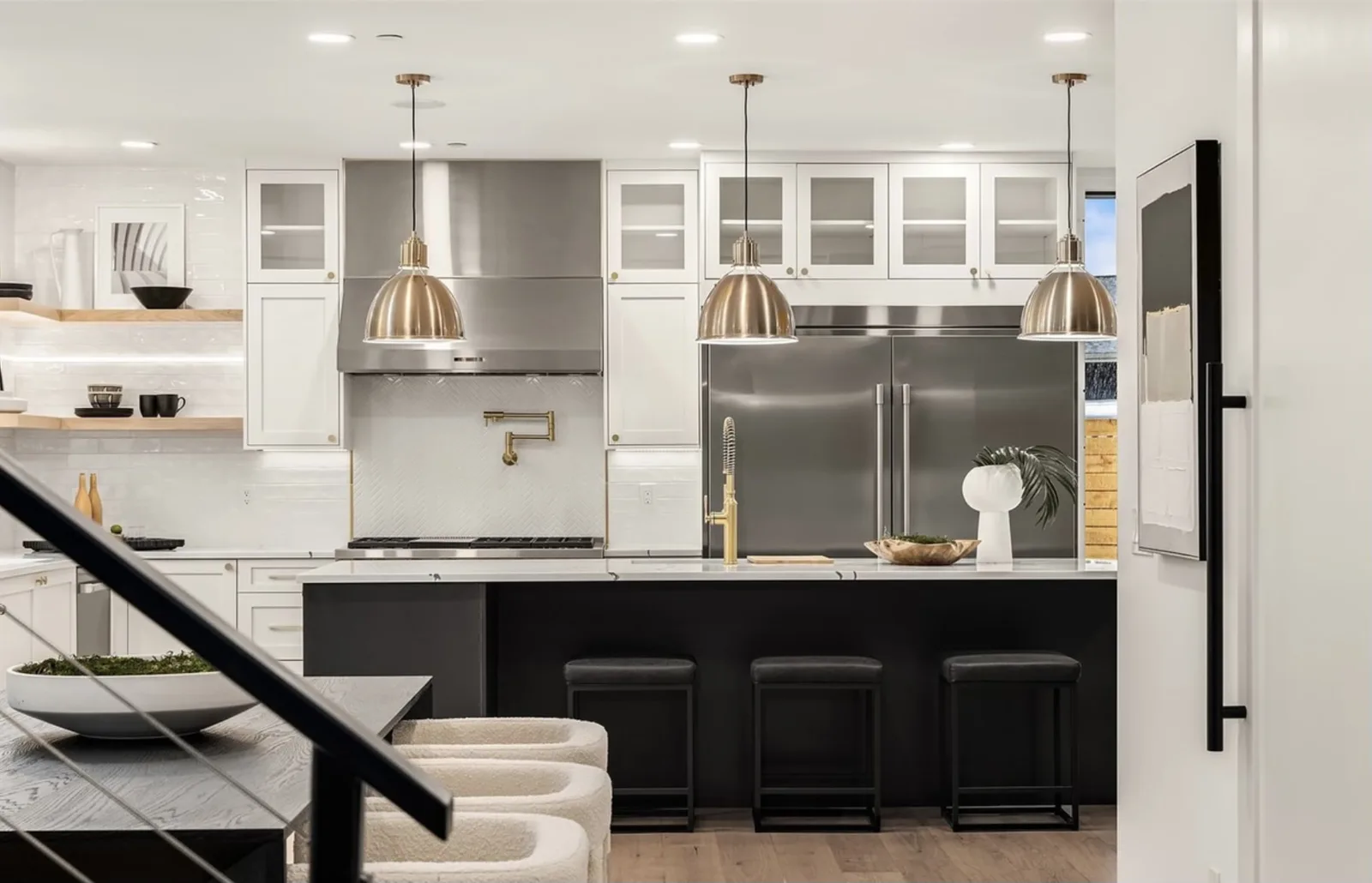 Kitchen with white shaker cabinets, brass pendants, stainless refrigerator, and a black island with stools
