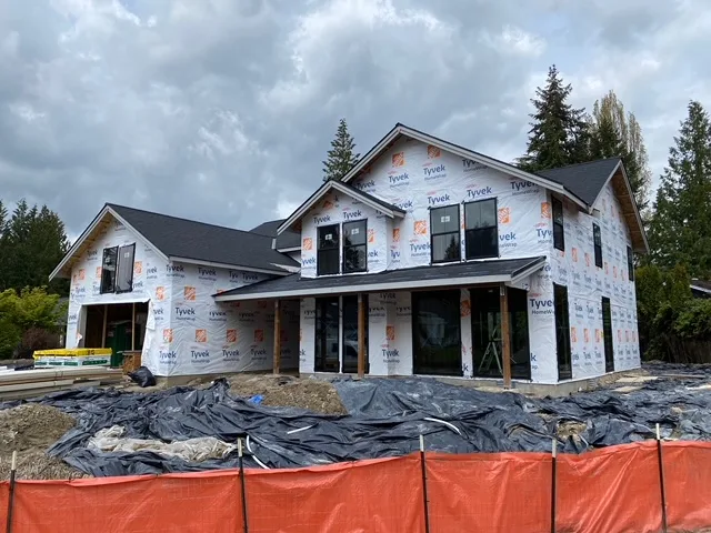 New Bellevue home wrapped in weather-resistive barrier with the roof on and silt fence along the street