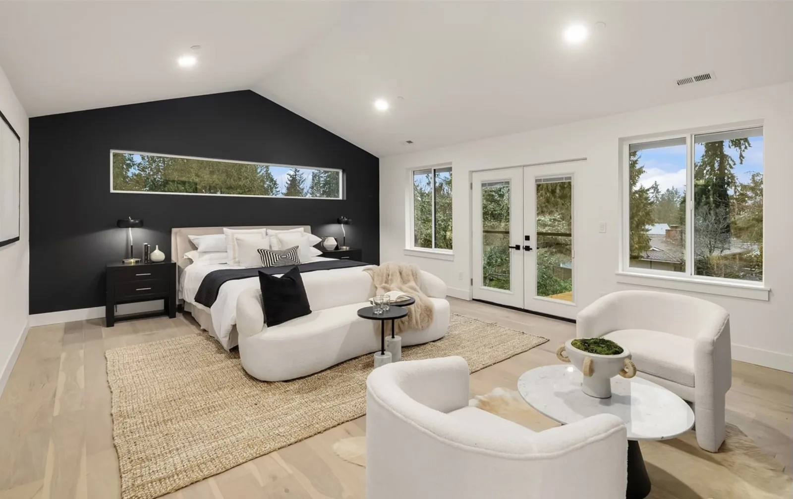 Bedroom sitting area with a black accent wall, French doors to the yard, and white armchairs