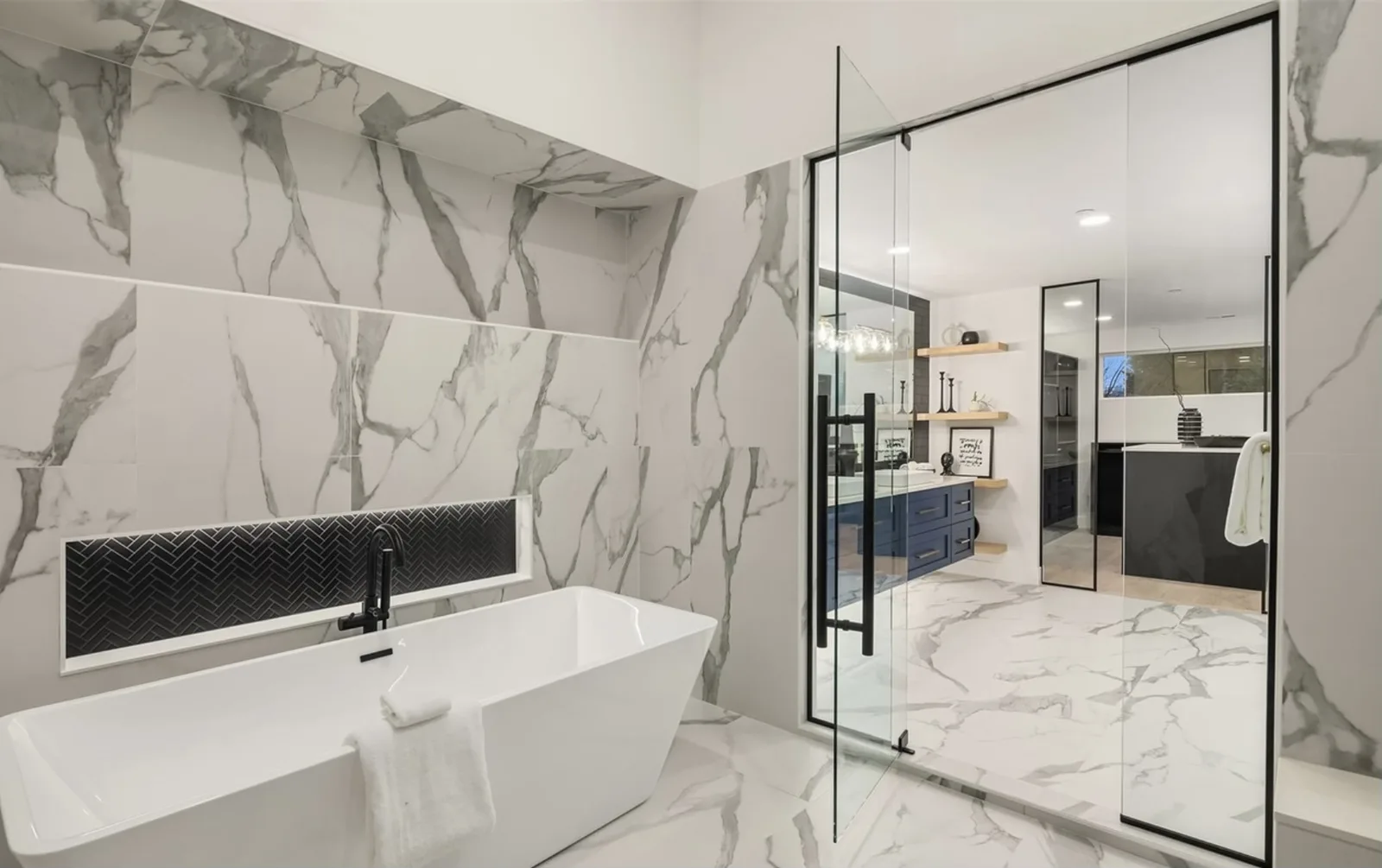 Marble primary bathroom with a freestanding soaking tub and black-frame glass shower
