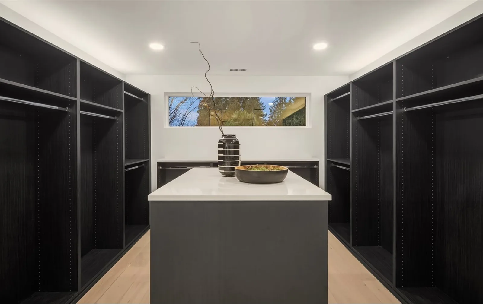 Walk-in closet with black built-in wardrobes and a center island