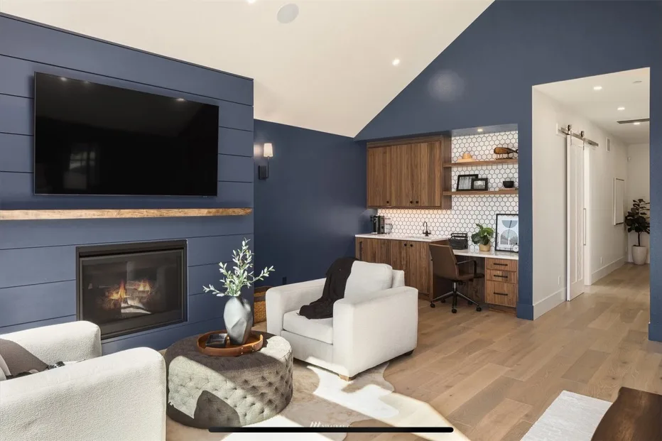 Family room with a navy shiplap fireplace wall, wall-mounted TV, vaulted ceiling, and built-in desk