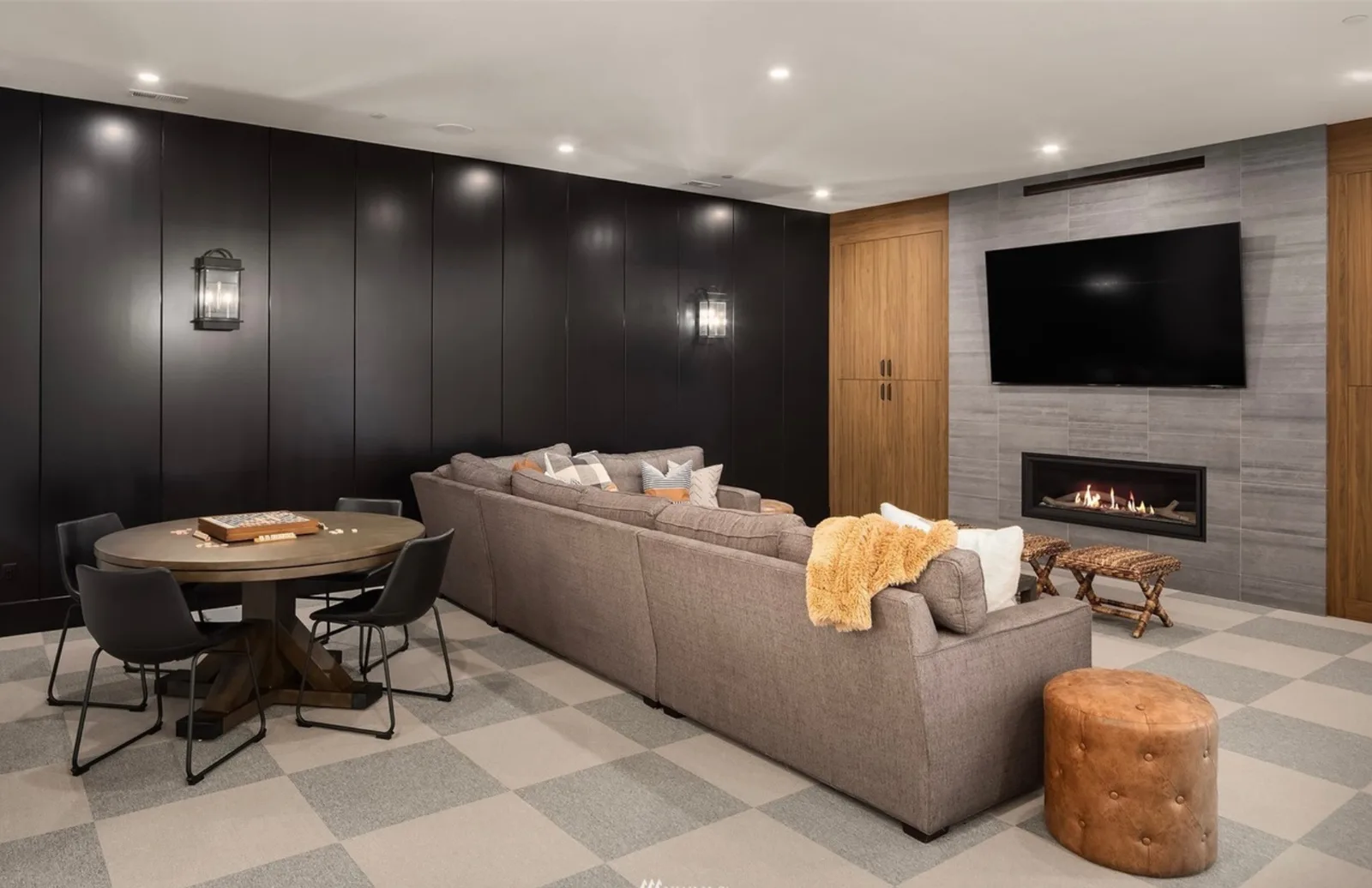 Paneled rec room with a sectional, linear fireplace with tile surround, TV, and game table