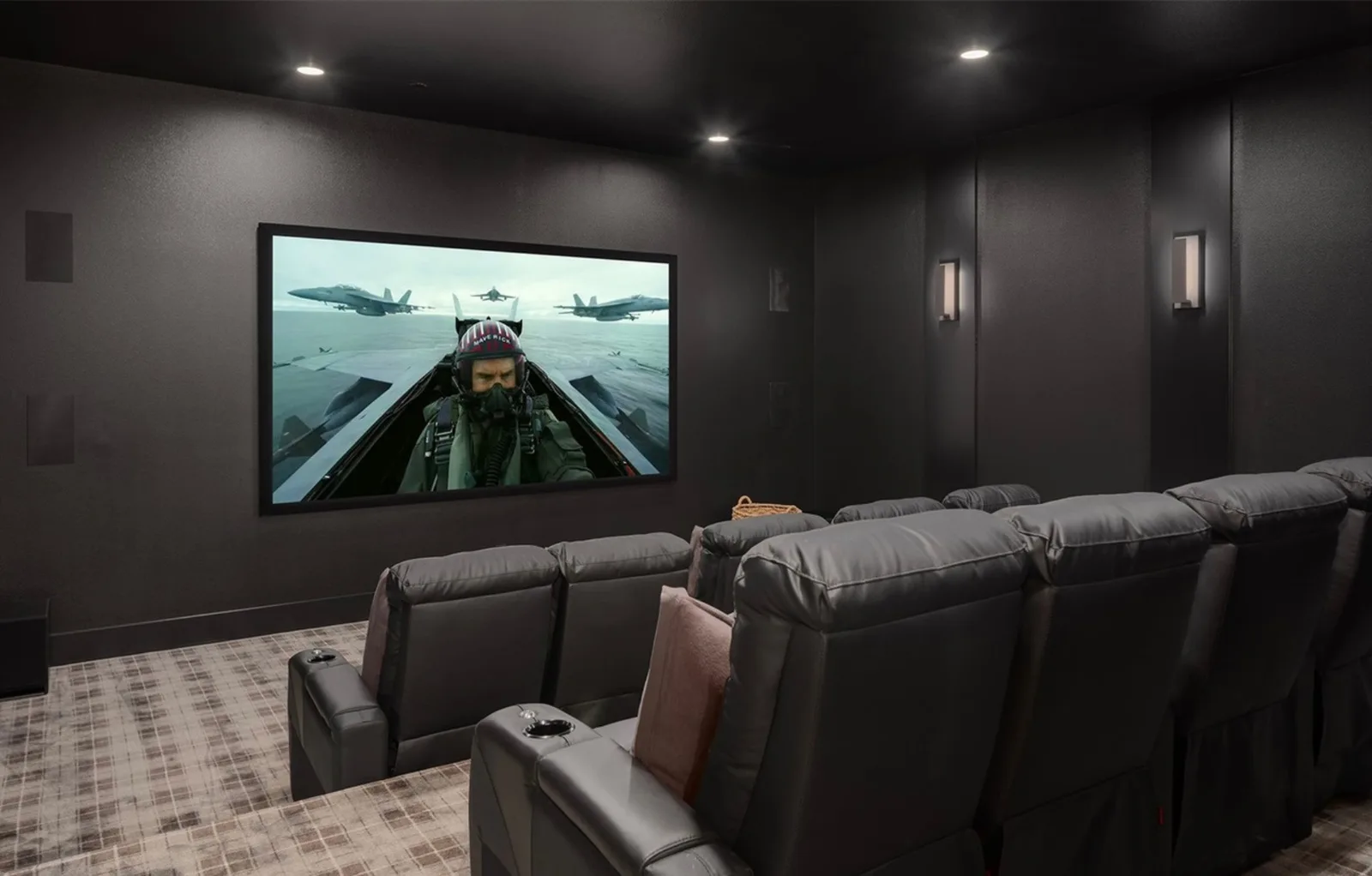 Home theater with dark walls, leather recliners, a large screen, and wall sconces