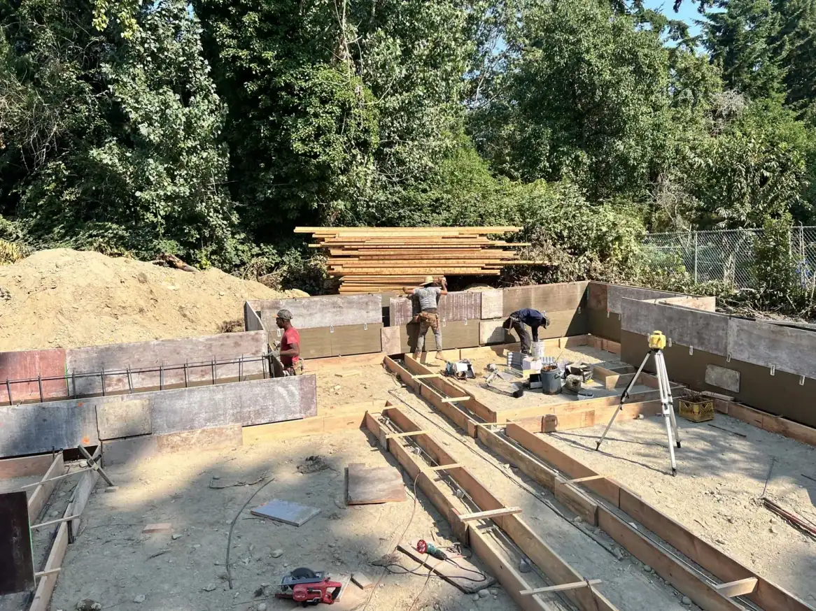Crew at the foundation wall forms with a laser level on a tripod