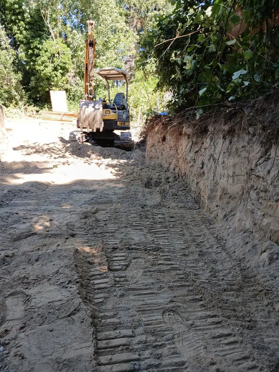 Excavator cutting the pad into the hillside and trenching for the foundation