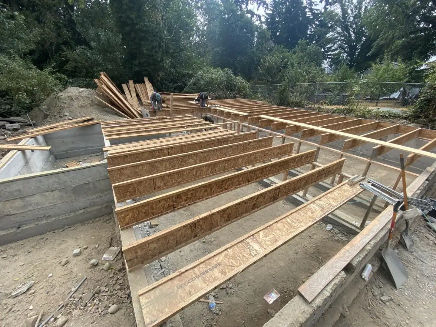 Engineered I-joist floor system being set over the new foundation walls