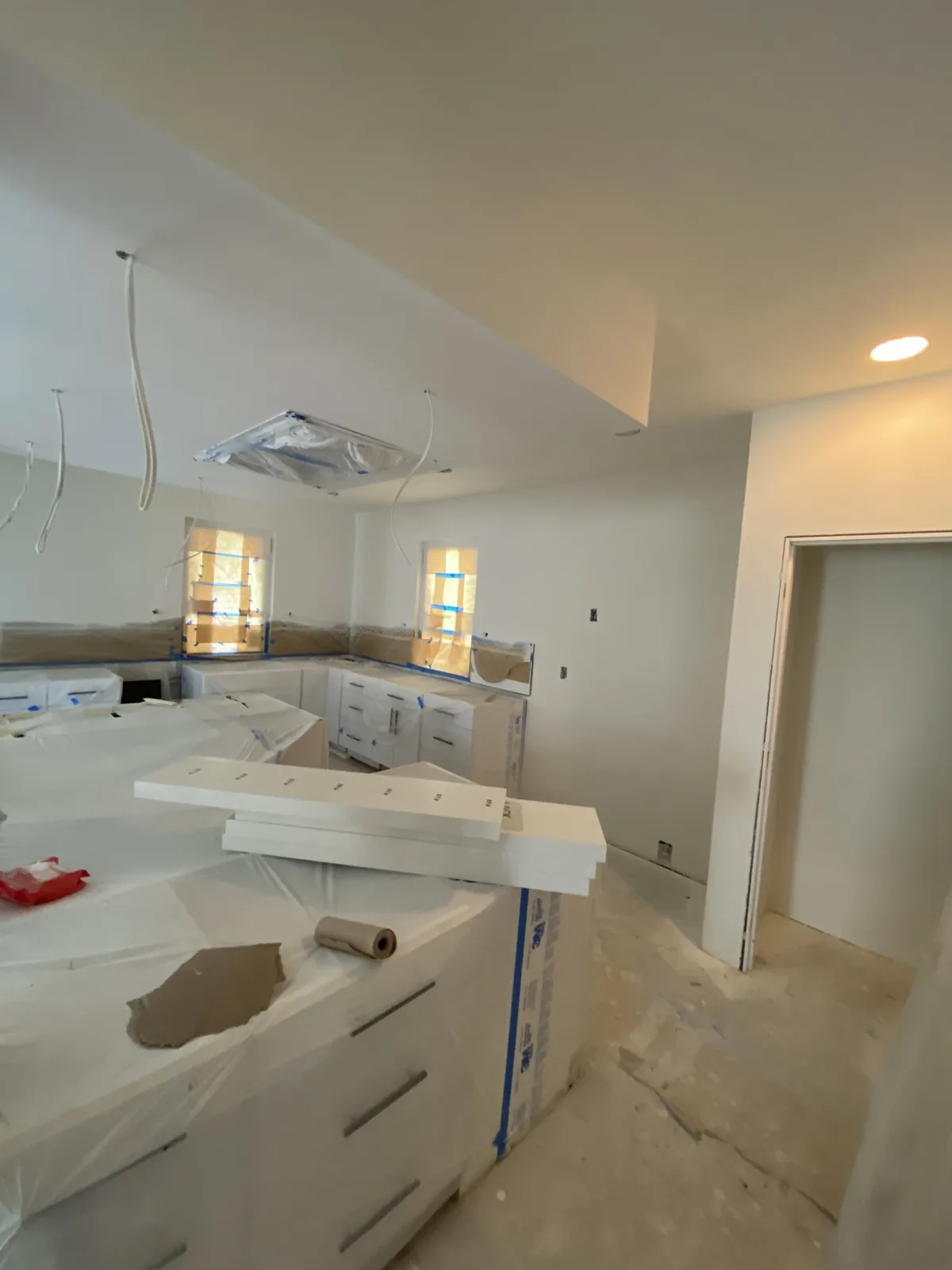 White kitchen cabinets installed at drywall stage before countertops