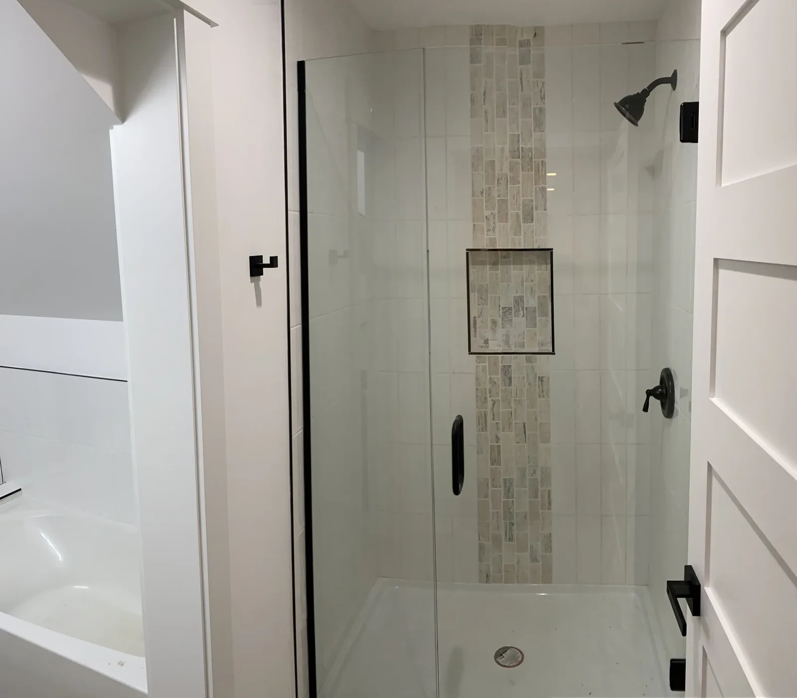 Tiled shower with a glass door, niche, and black fixtures
