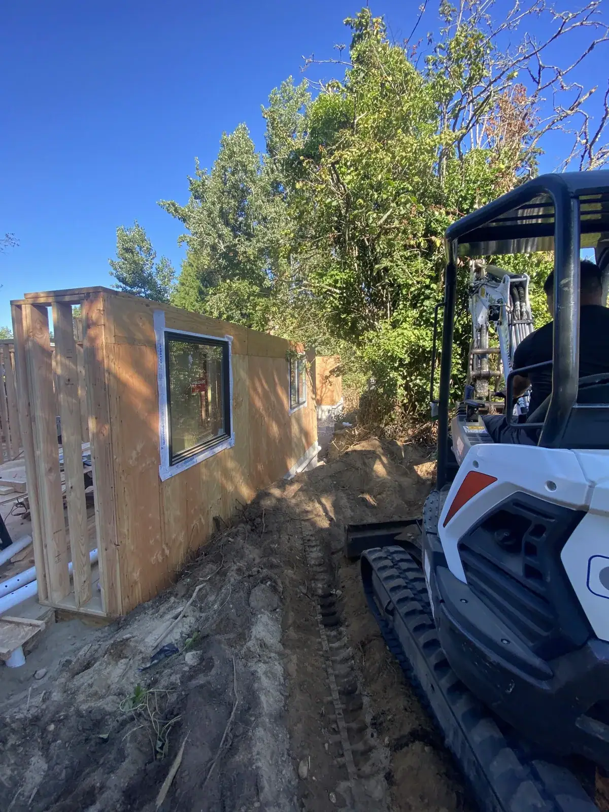 Framed wall panel with a window opening beside a Bobcat skid steer