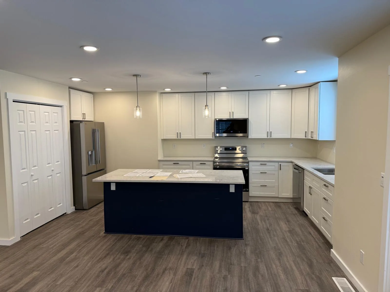 Kitchen with a navy island, stainless refrigerator, and white cabinets