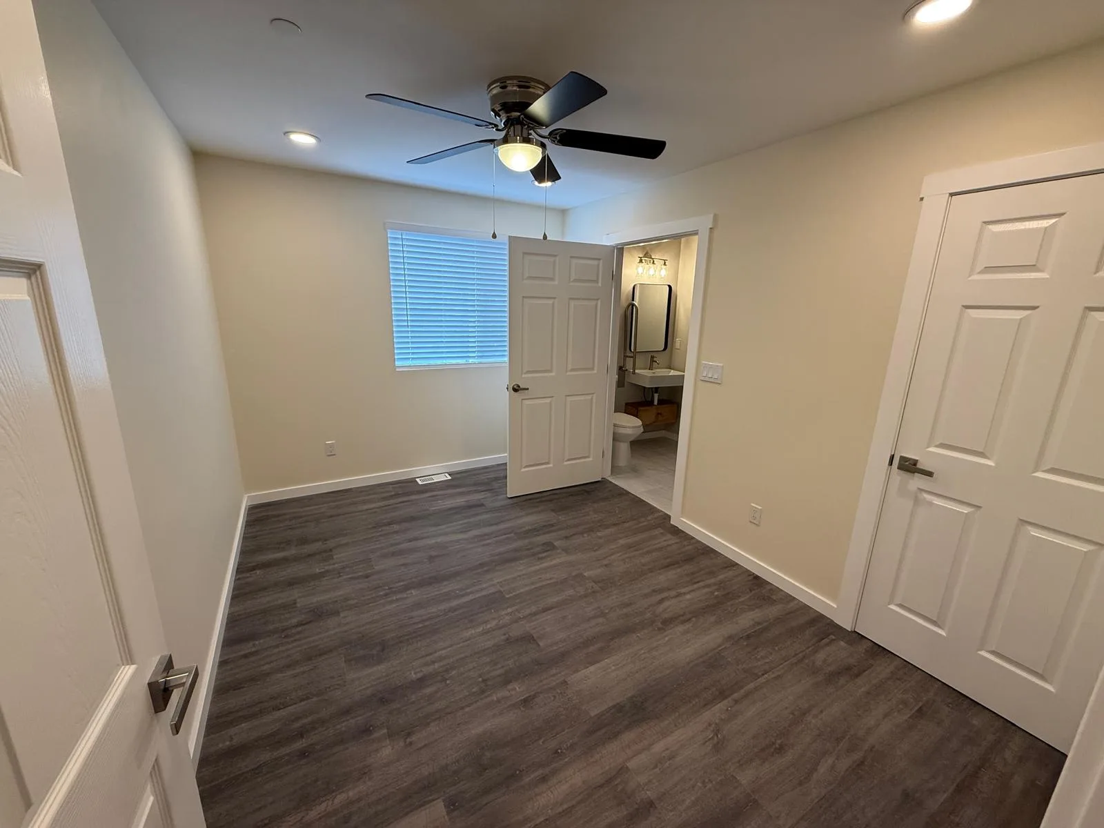 Bedroom with a ceiling fan and the door to its attached bathroom