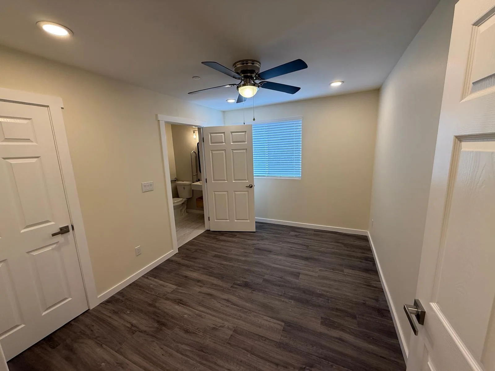 Bedroom with an ensuite bath door open and LVP flooring