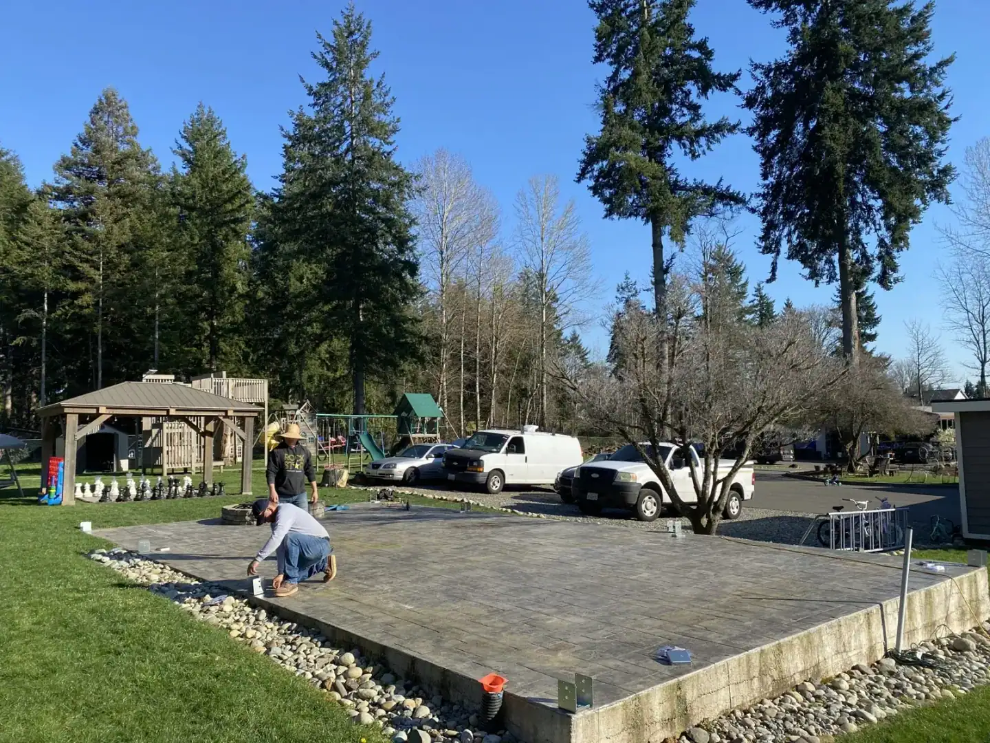 Existing stamped-concrete patio with a stone fire pit as the crew lays out post positions in Coeur d'Alene