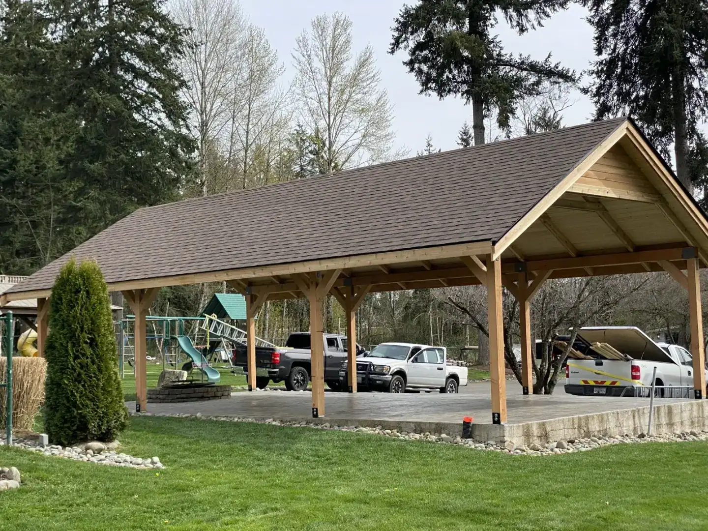Wide view of the finished timber pavilion with vehicles parked beyond