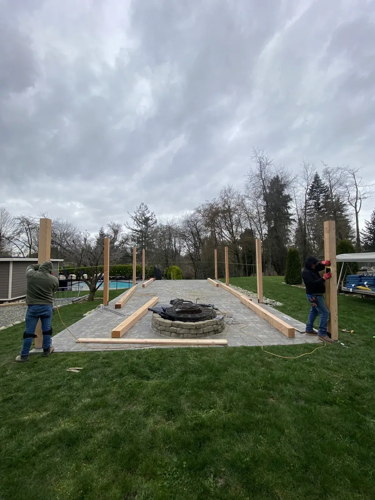 Cedar posts standing around the fire pit as the crew plumbs and braces them