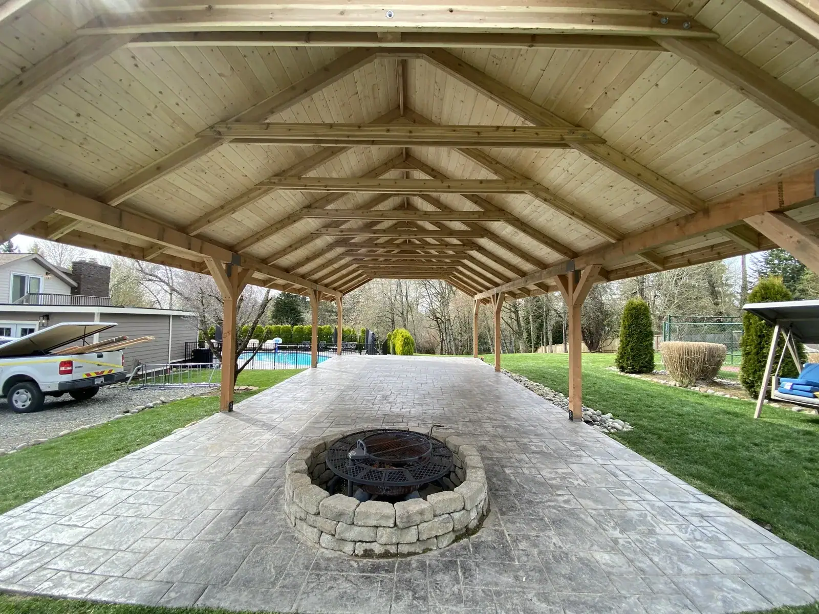 Stone fire pit centered under the pavilion ridge on the stamped patio