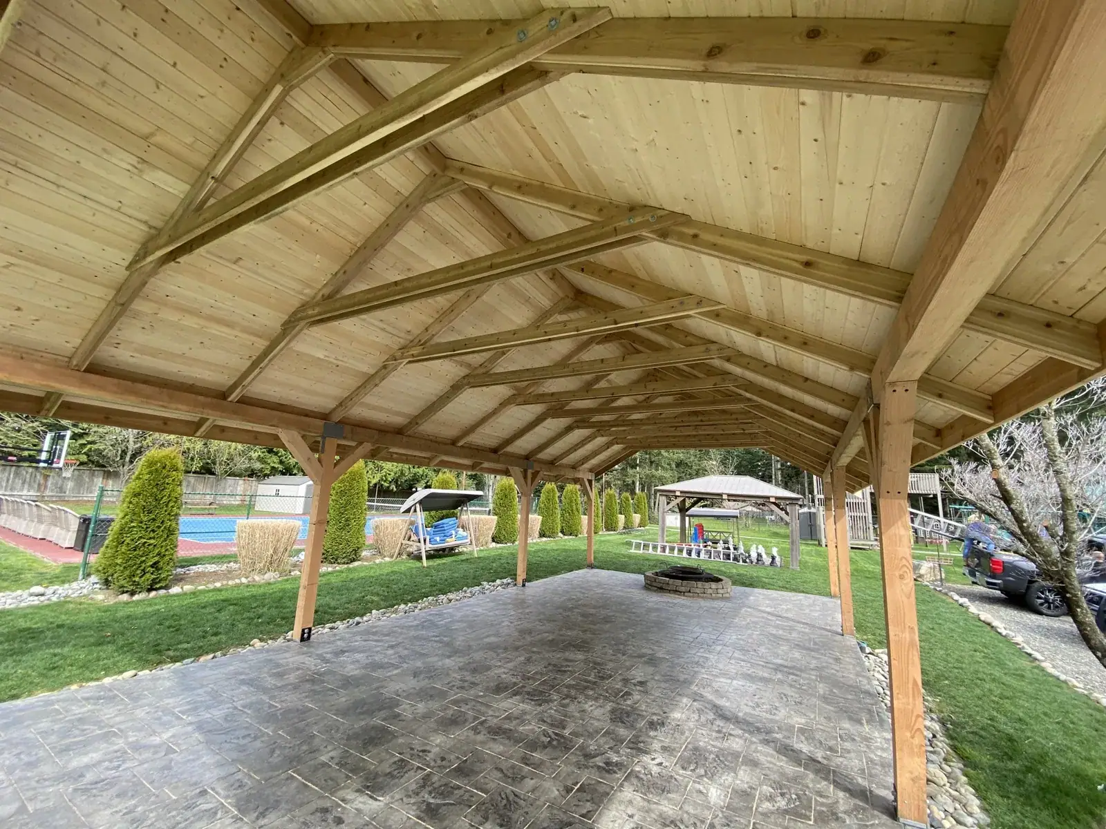 View out from under the finished roof toward the pool, trusses exposed overhead