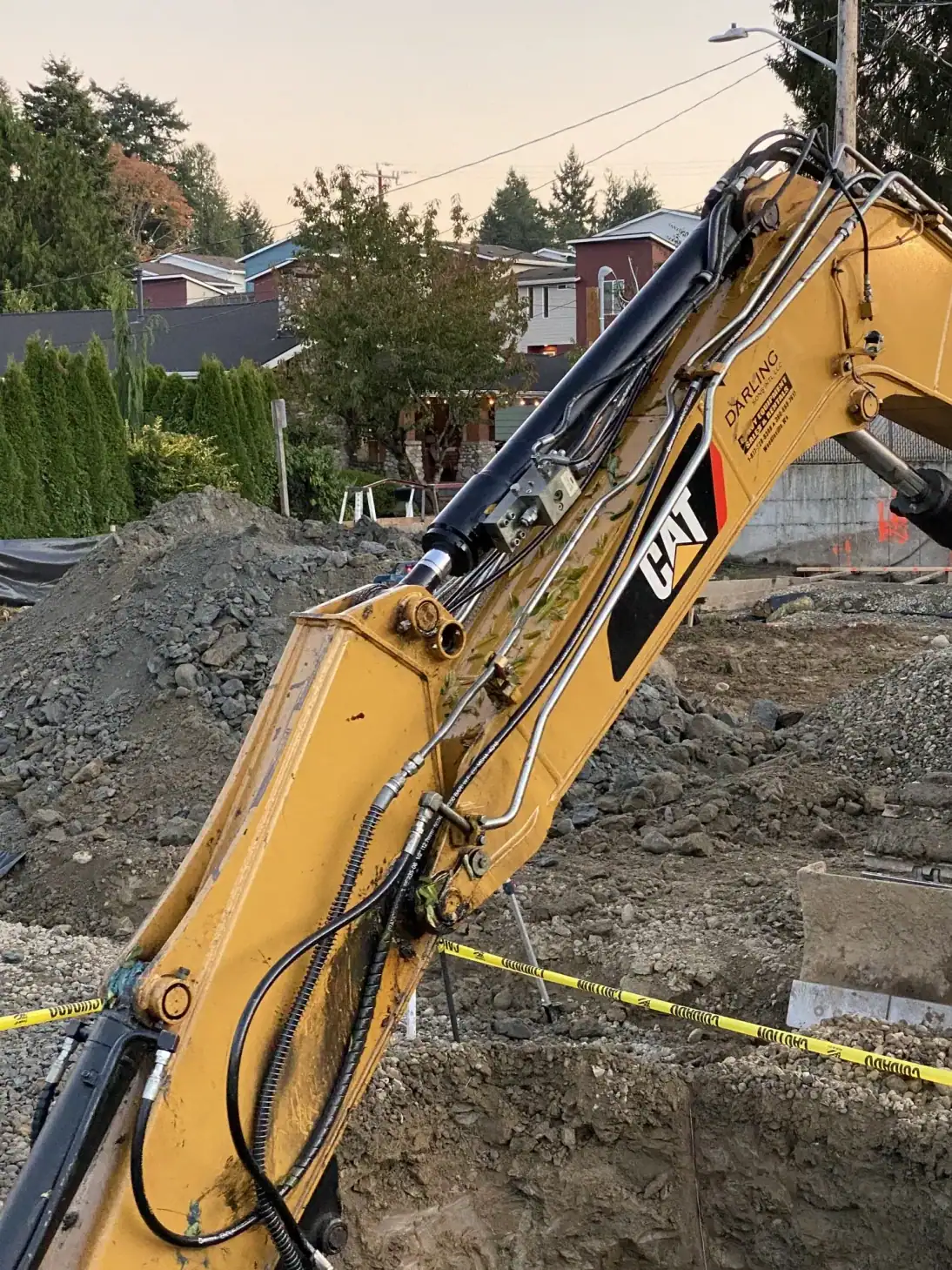 Excavator arm reaching over the excavation with the neighboring building behind