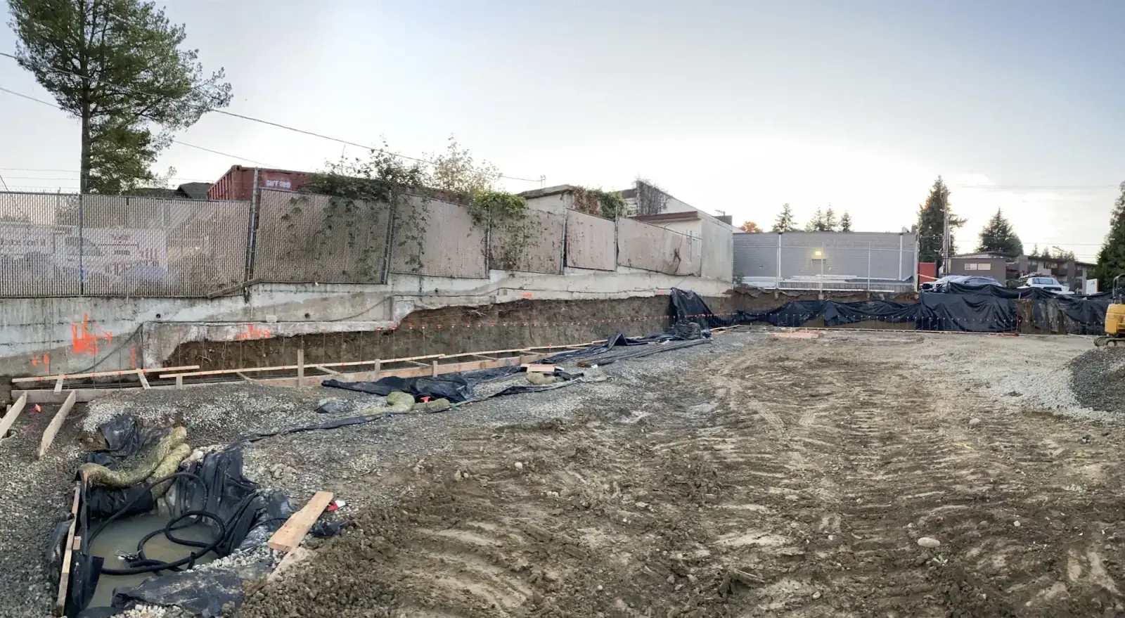 Graded pad with footing forms set along the wall and a sound wall in the background