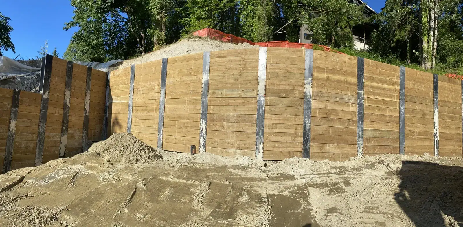 Long run of timber-lagging soldier-pile wall following the grade