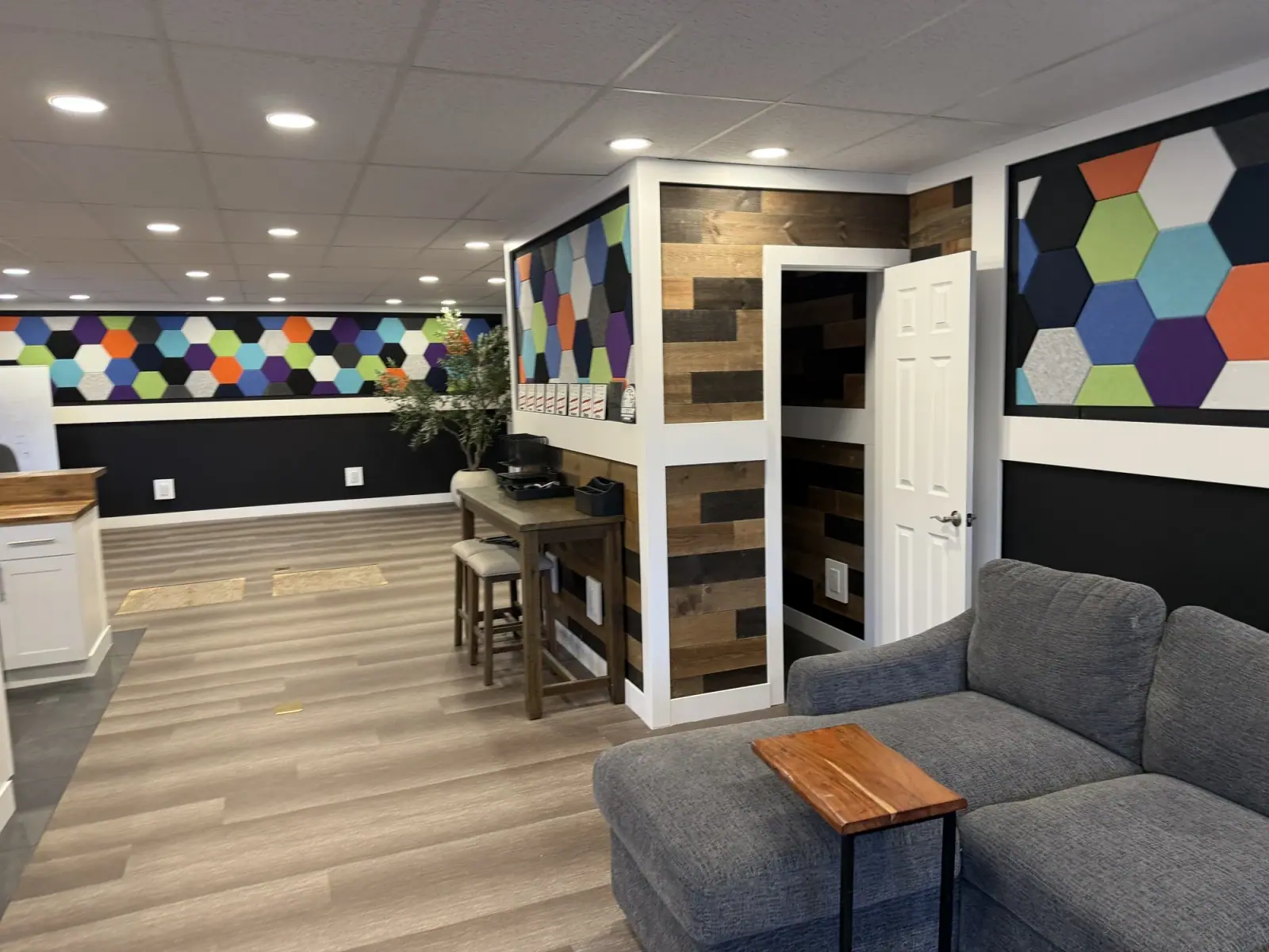 Colorful hexagon acoustic panel wall above a bar-height counter and sofa