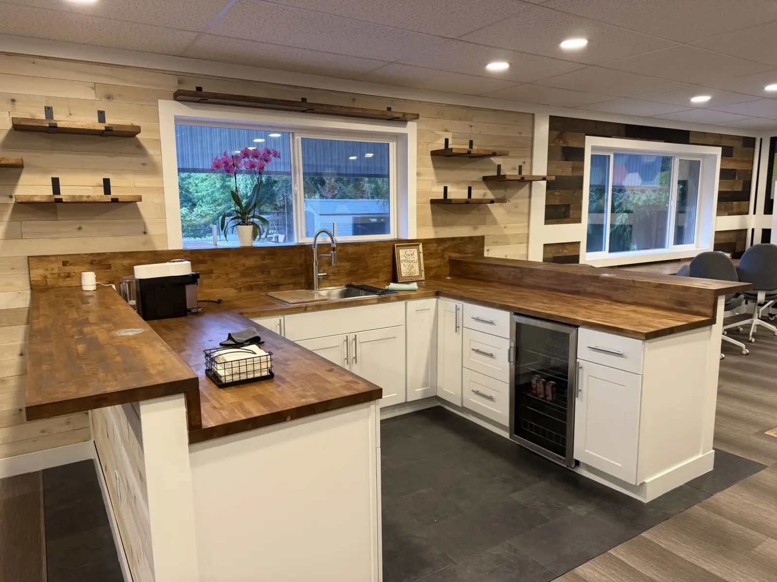Kitchenette with white shaker cabinets, butcher-block counters, a beverage fridge, sink, and floating shelves