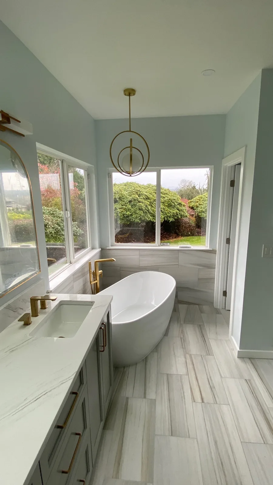 Freestanding soaking tub beneath garden windows beside the vanity