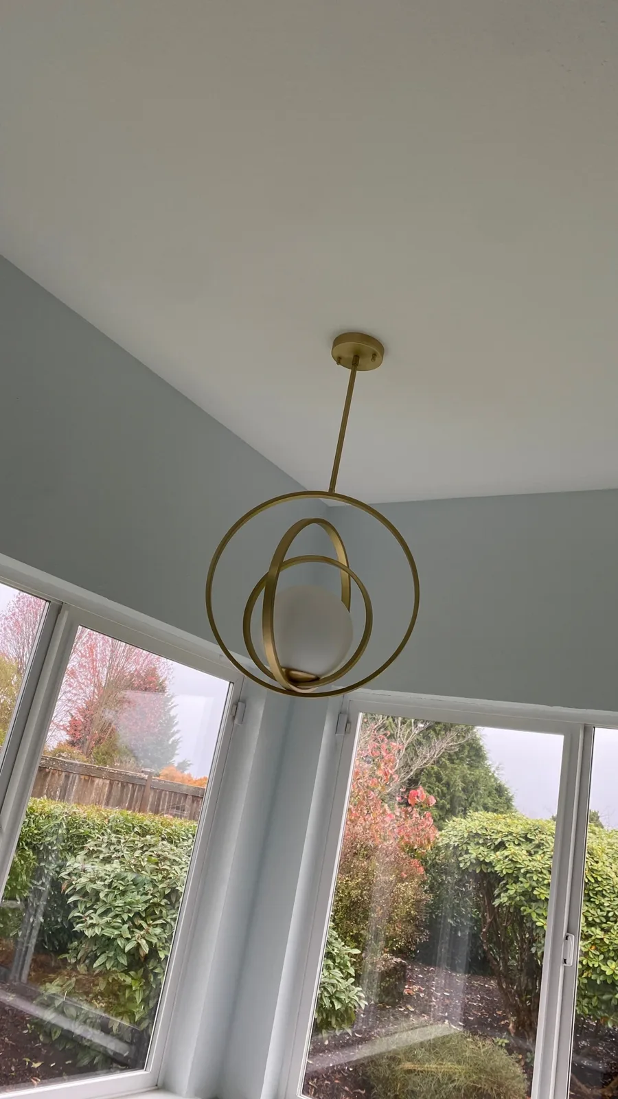 Brass ring pendant hanging over the tub bay in front of garden windows