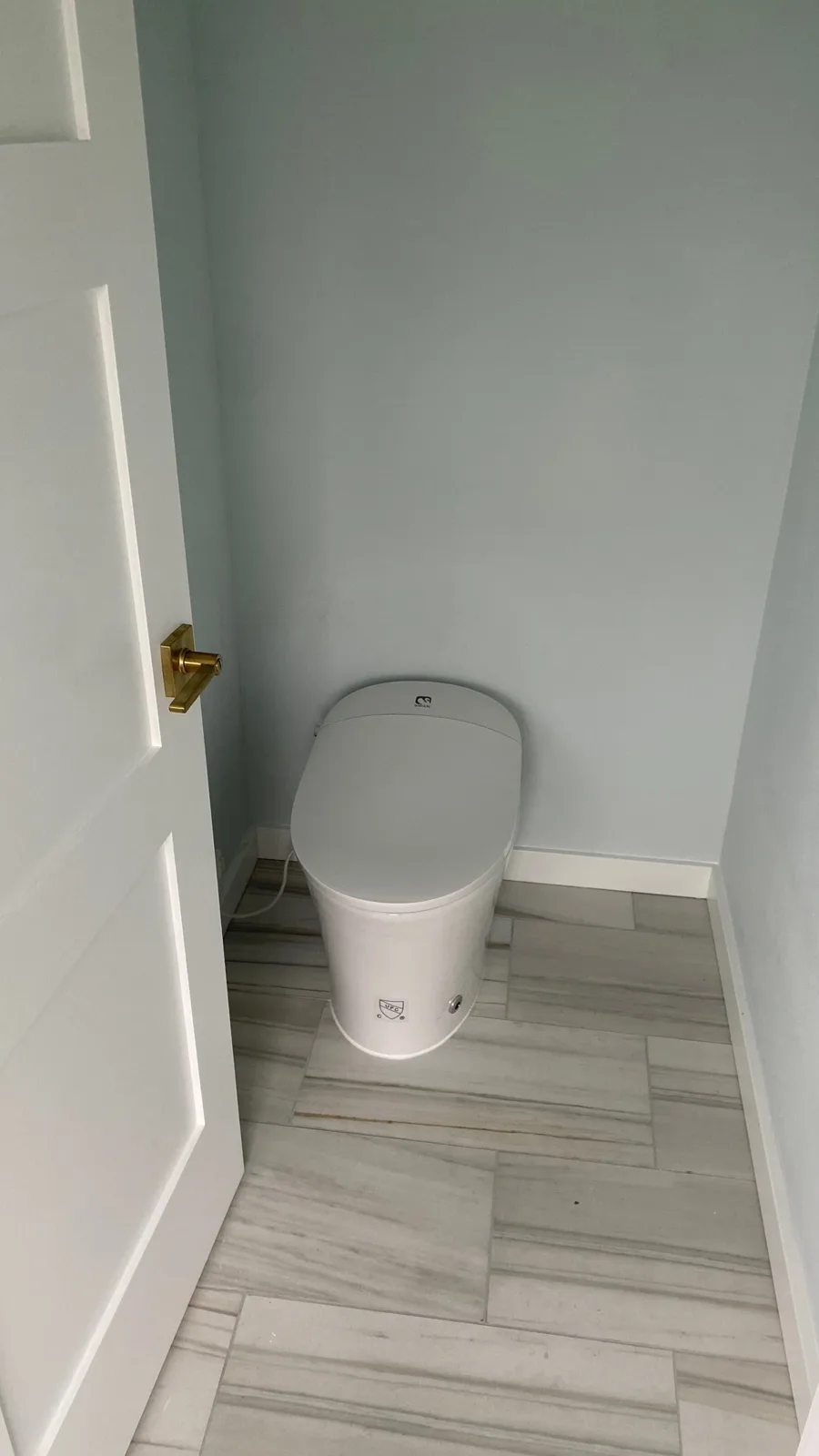 Separate water closet with a toilet on porcelain plank tile