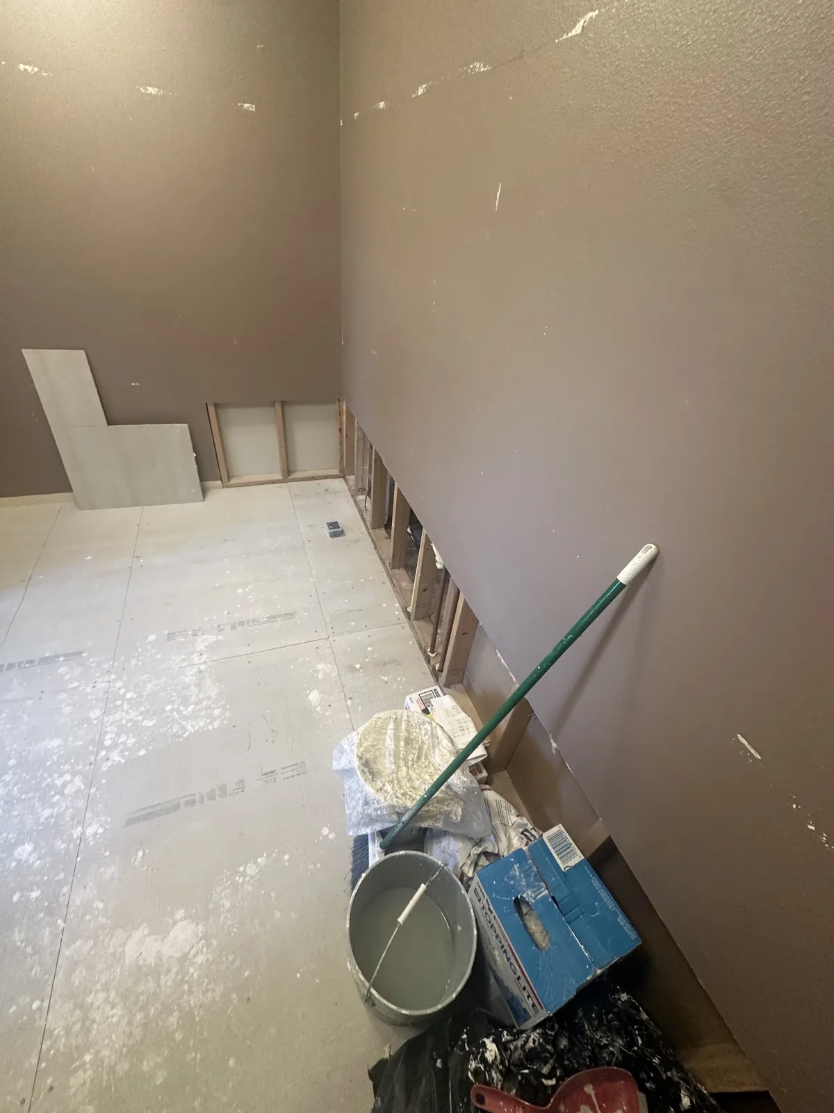 Gutted bathroom floor with old finishes removed and buckets staged