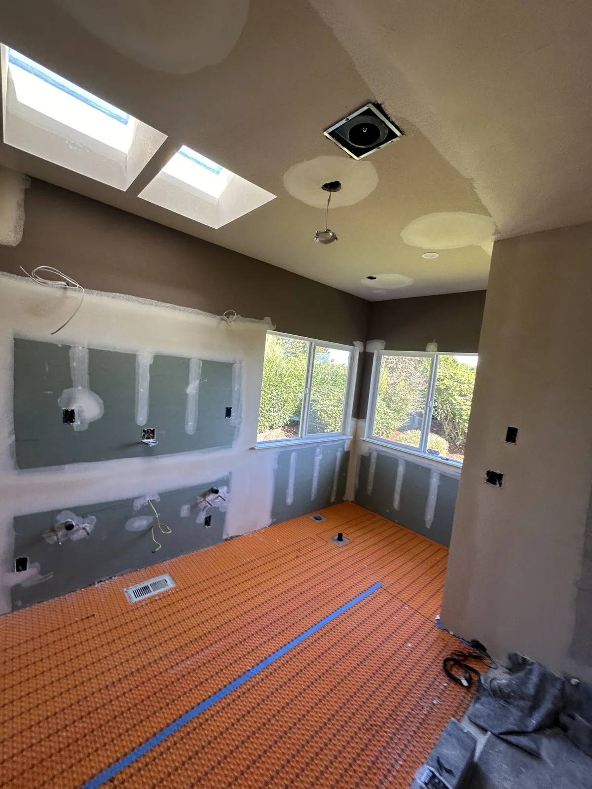 Orange uncoupling membrane laid over the floor with cement board on the walls and a skylight above