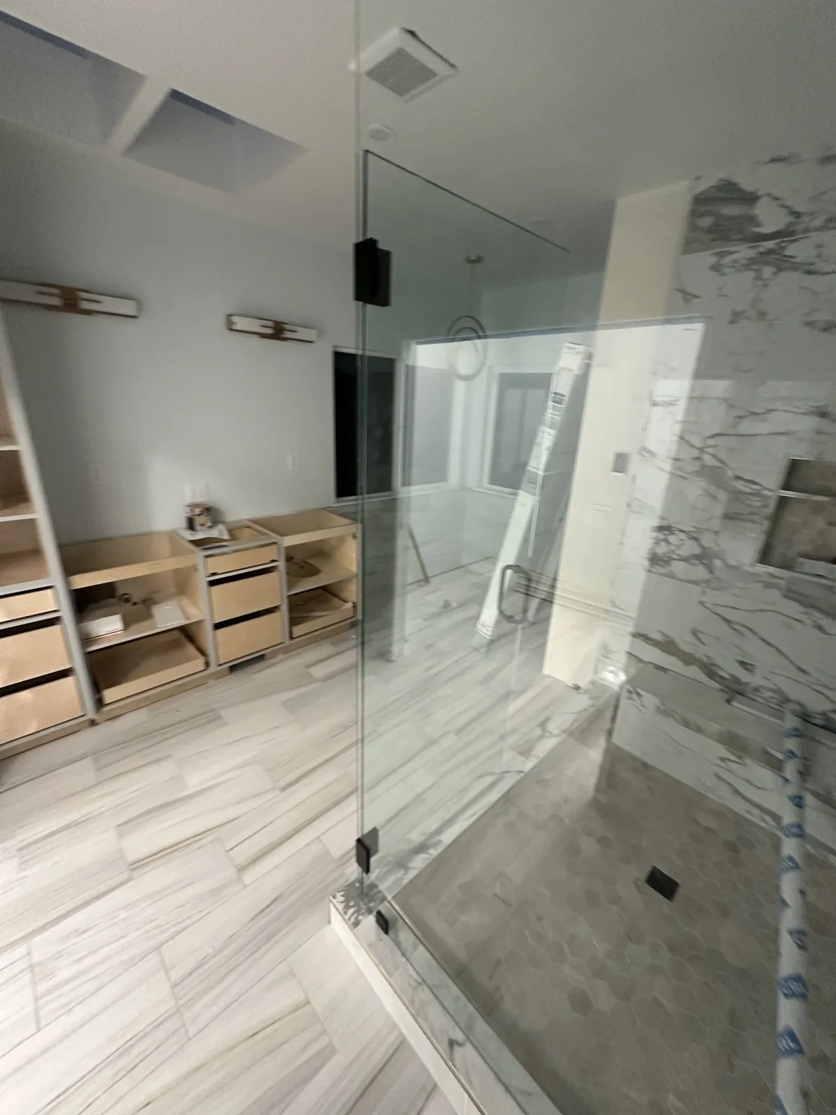 Frameless glass shower enclosure installed with vanity bases set and no tops yet