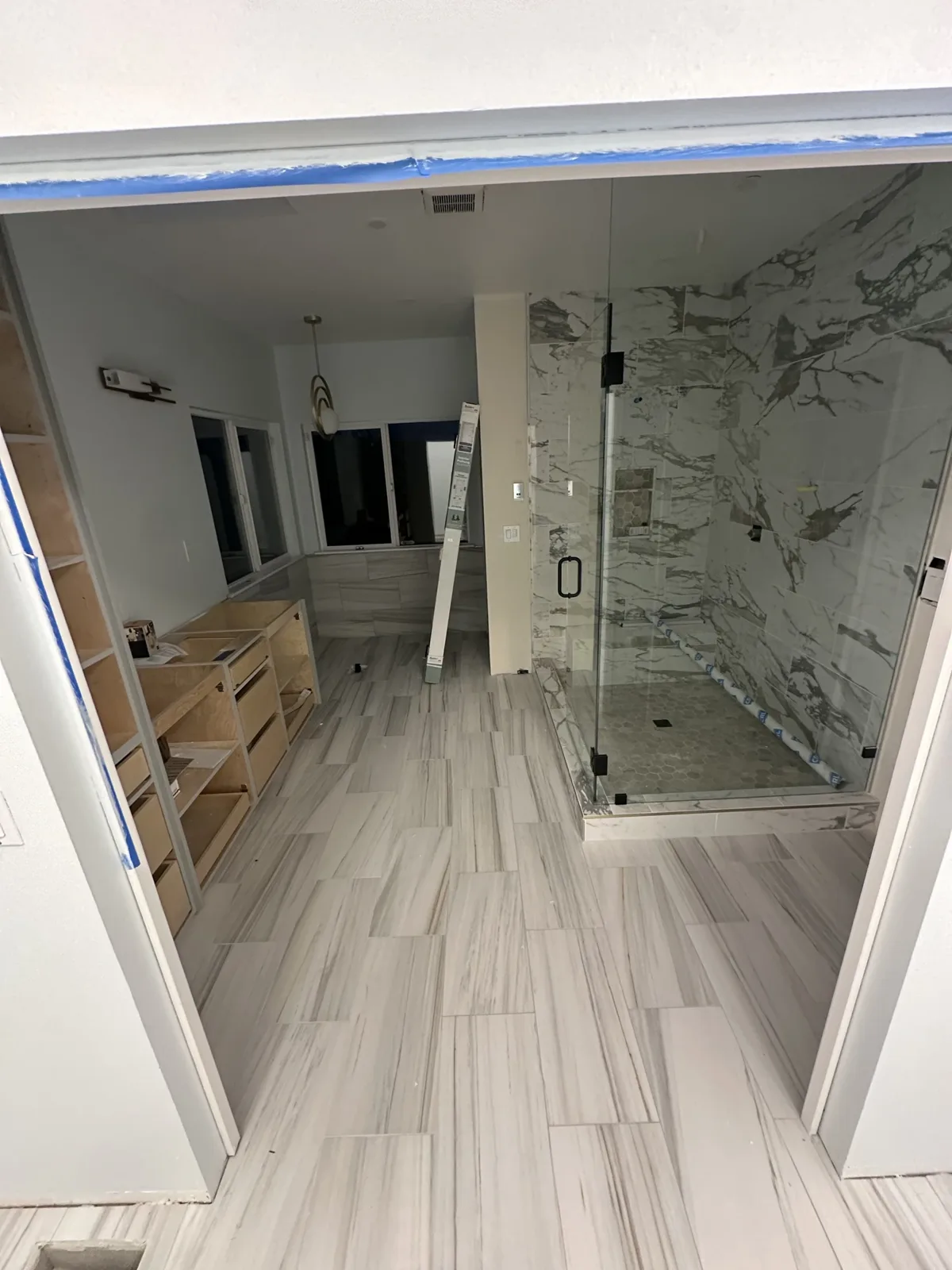Gray vanity bases installed beside the glass shower on porcelain plank tile