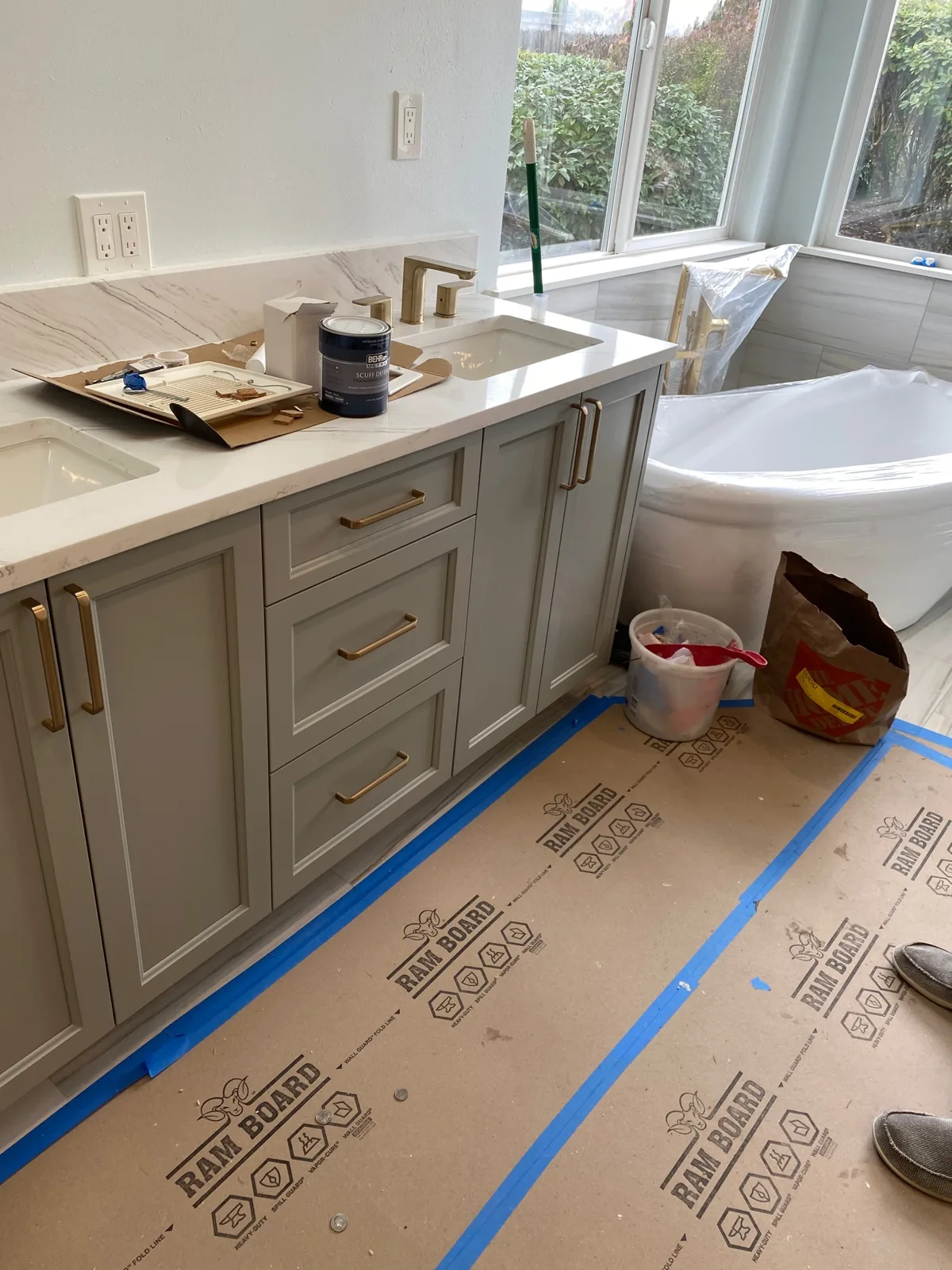 Quartz vanity top installed with the freestanding tub set in the window bay under floor protection