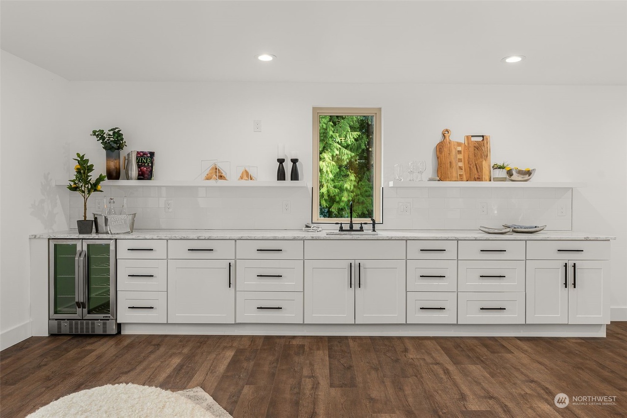 Third-level bonus room wet bar with white cabinets, beverage fridge, and sink