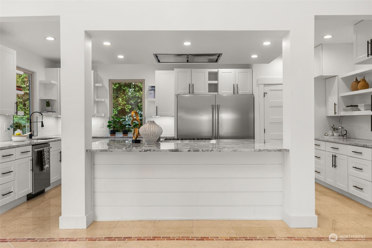 Kitchen viewed from the great room through the arched opening, with a marble breakfast bar
