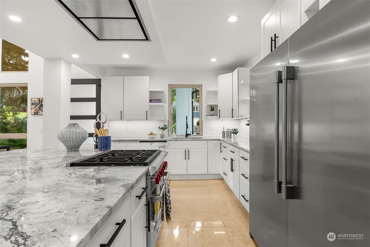 Kitchen with marble-look quartz counters, gas cooktop, stainless refrigerator, and white shaker cabinets