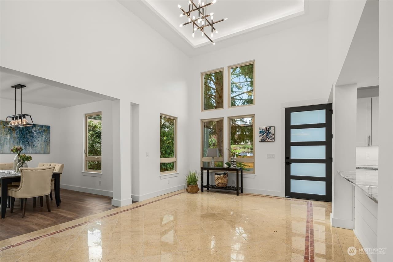 Great room with tall windows, chandelier, and dining table on polished tile