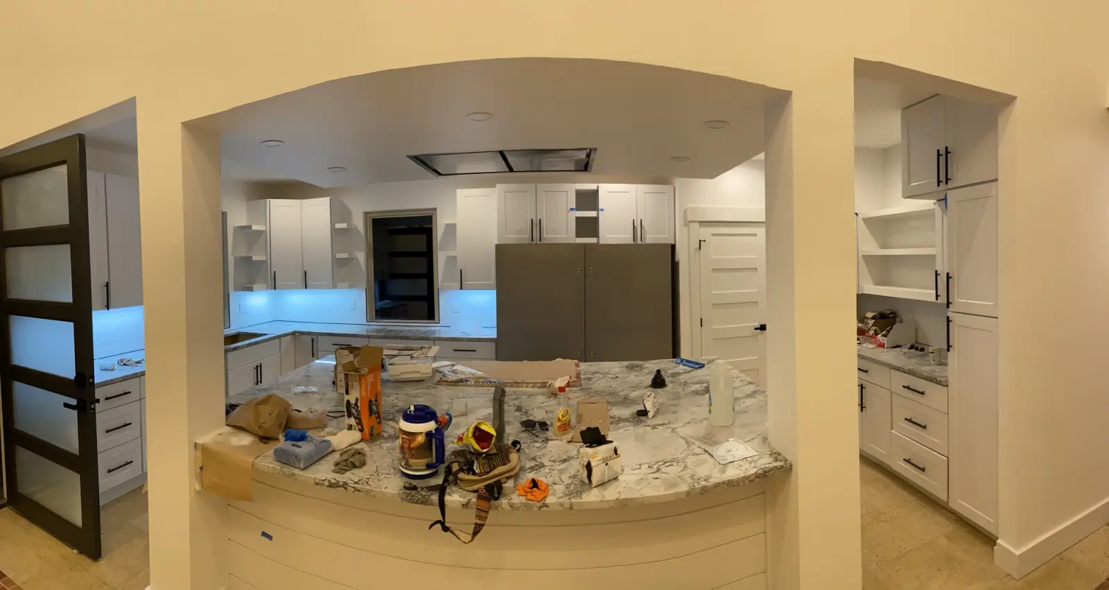 Kitchen with white cabinets and the arched opening at finish stage, island still covered