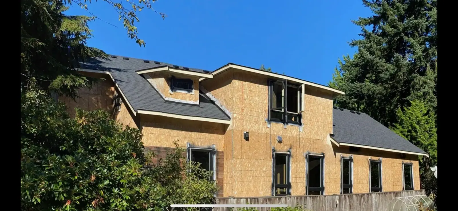Two-story house sheathed in OSB with the roof on, ready for weather barrier